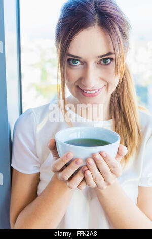 Woman in apartment takes a break holding tea cup Stock Photo