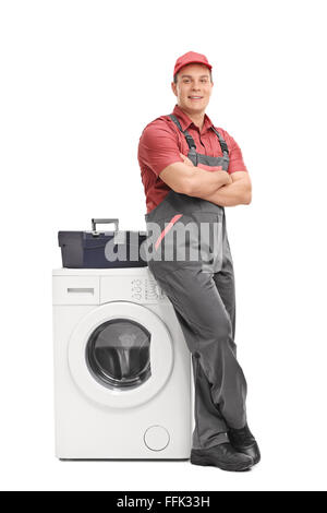 Full length portrait of a young male repairman leaning on a washing machine isolated on white background Stock Photo