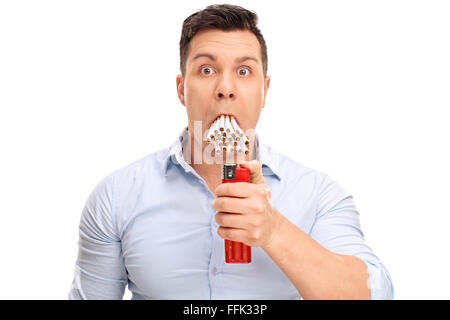 Young man lighting up a bunch of cigarettes in his mouth isolated on white background Stock Photo