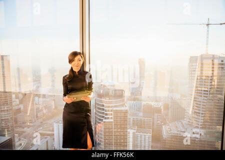 Female architect in office with urban skyline in background Stock Photo