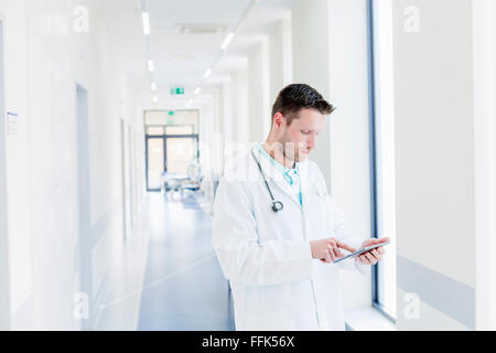 Doctor in hospital corridor using digital tablet Stock Photo
