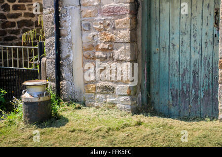 Milk churn outside barn door, Carlton, Yorkshire Dales, England Stock Photo