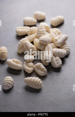 Uncooked homemade gnocchi, on a grey background, with flour. Stock Photo