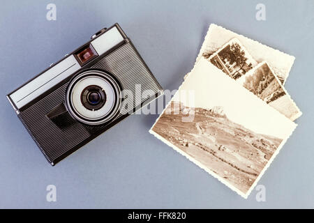 Vintage photo camera and old photos on a gray table Stock Photo