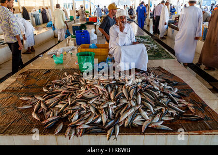 An Omani Man In Traditional Dress Sells Fish At The Fish Market, Muttrah, Muscat, Sultanate Of Oman Stock Photo