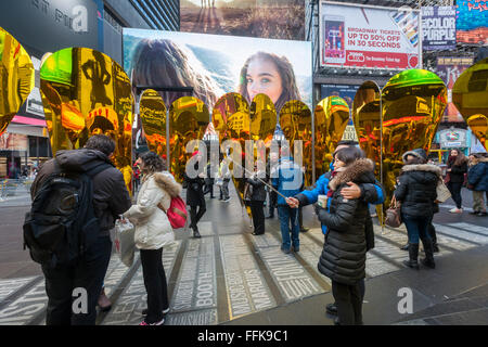 Visitors do selfies with their reflections in 'Heart of Hearts', the winner of the Times Square Valentine Heart Design in Times Square in New York on Tuesday, February 9, 2016. The sculpture by Collective-LOK creates a golden kaleidoscopic space that mirrors the cacophony and visual stimulation that attracts so many visitors to Times Square. The sculpture will be on view until March 6. (© Richard B. Levine) Stock Photo