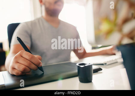 Hand of male designer working at his desk using stylus and digital graphics tablet. Stock Photo