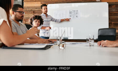 Young african woman sitting at conference table during a business presentation. Team of creative professionals in a meeting in b Stock Photo