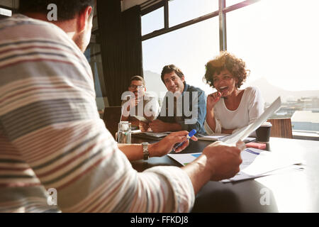 Shot of mixed race young people sitting at a table discussing new and creative business ideas. Smiling african woman sitting wit Stock Photo
