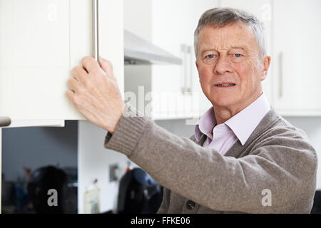 Forgetful Senior Man Looking In Cupboard Stock Photo