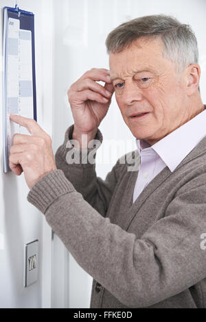 Confused Senior Man With Dementia Looking At Wall Calendar Stock Photo