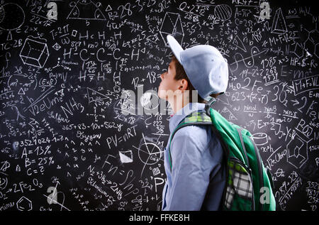 Boy  with schoolbag against big blackboard with mathematical sym Stock Photo