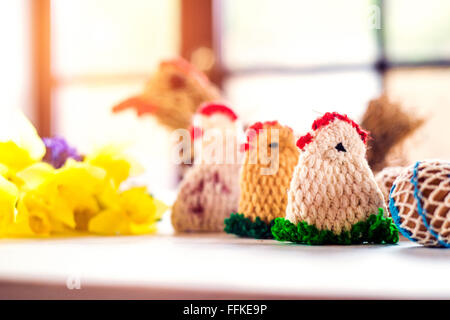 Colorful crocheted Easter chickens and daffodil laid on table Stock Photo