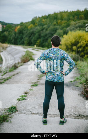 Runner resting, path in green nature, back view Stock Photo