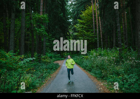 Man running on path in an old green forest. Stock Photo