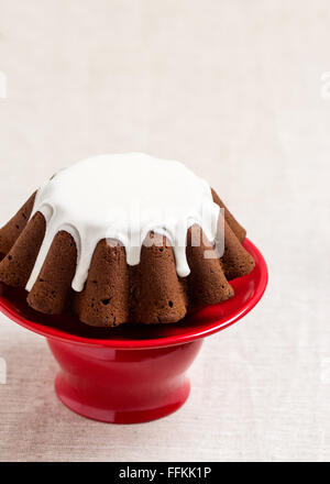 Chocolate cake with white frosting on a red stand. Selective focus. Stock Photo