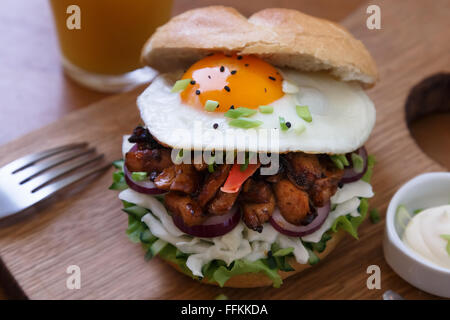 Homemade burger with fried egg and spicy fries on wood board. Stock Photo