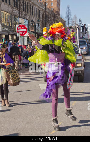 A colorfully costumed woman in a Mardi Gras parade throws colorful plastic beads to spectators Stock Photo