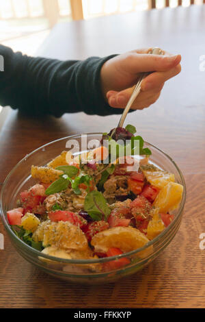 Close up of a young woman's hand holding a fork and digging into a healthy, colorful  and creative salad Stock Photo