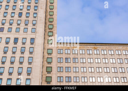 Facade of a big multi-storey building with several windows and blue sky in the background Stock Photo