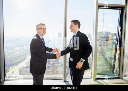Two businessmen shaking hands in modern office Stock Photo