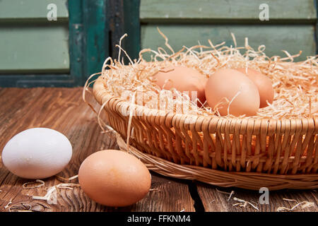 Side view of easter nest with raw uncolored eggs in front of green window. Stock Photo