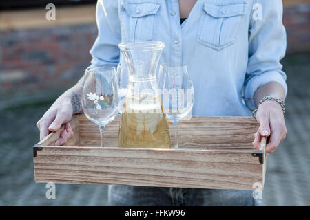Woman serving white wine on tray Stock Photo