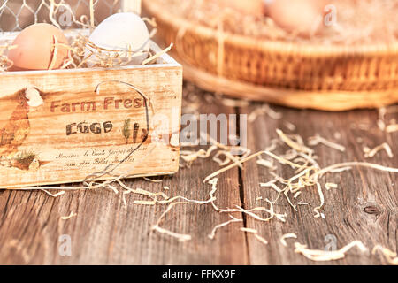 Eggs in an wooden egg box on a wooden talbe with nest in background Stock Photo