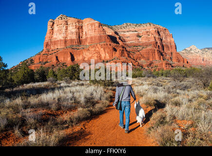 Hiker and dog walk toward the Courthouse Butte at sunset Stock Photo