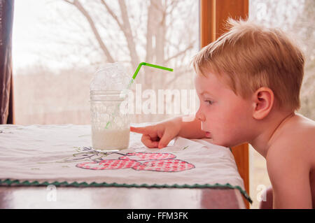 Child pointing at glass half full Stock Photo