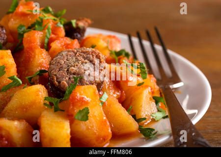 Potato and Sausage Dinner on white plate with silver fork Stock Photo