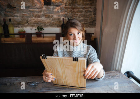 Happy woman reading menu in restaurant Stock Photo