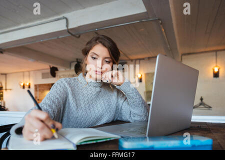 Woman working with laptop computer and notepad in cafe Stock Photo