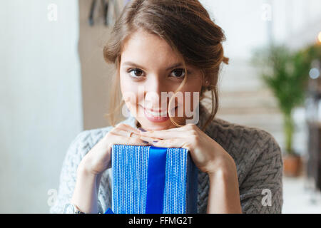 Closeup portrait of a smiling woman with gift box looking at camera Stock Photo