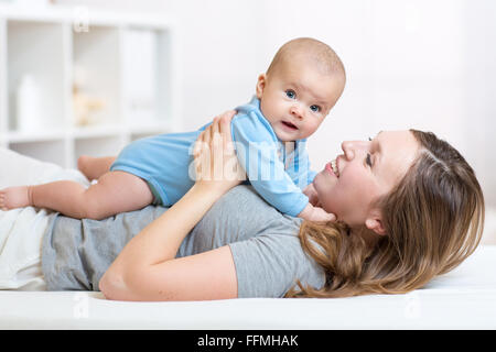 baby and smiley mother lying in bed Stock Photo