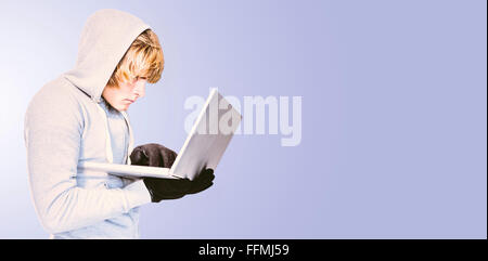 Composite image of focused man with hoodie typing on laptop Stock Photo