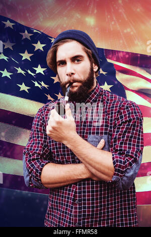 Composite image of hipster wearing knitted hat smoking pipe Stock Photo