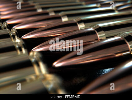 A macro close up view of a row of regular scratched brass and copper bullets on an isolated black background Stock Photo