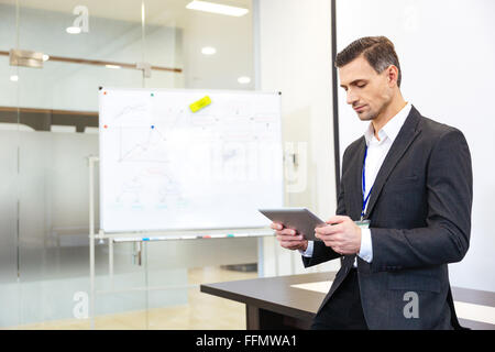 Focused businessman standing and using tablet in office Stock Photo