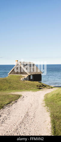 Fishing cottages against the sun and cobble beach in Osterlen, Skane / Scania, Sweden. Scandinavia. Stock Photo