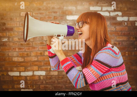 Composite image of smiling hipster woman shooting through megaphone Stock Photo