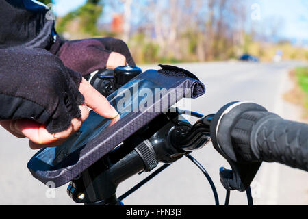 closeup of a young man using a smartphone mounted in the handlebar of a bicycle Stock Photo
