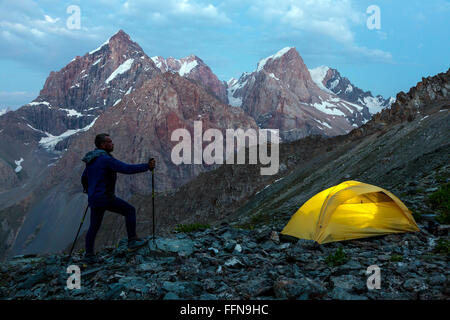 Hiker walking toward illuminated climbing tent Stock Photo