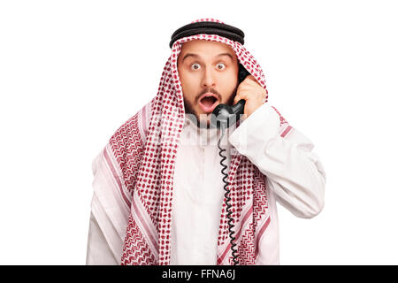 Studio shot of a surprised young Arab speaking on telephone isolated o white background Stock Photo