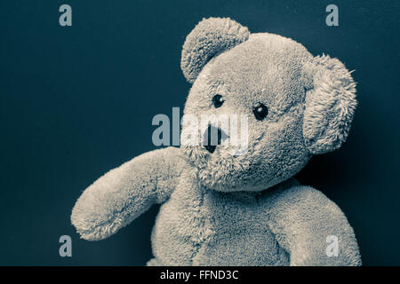 Lonely teddy bear on a dark background looking sad Stock Photo