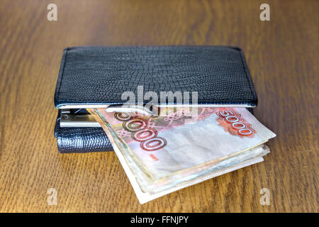 Wallet with cash lying on a wooden table Stock Photo