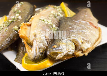 Baked trout fish served on a plate with lemon and spices Stock Photo