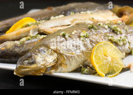 Baked trout fish served on a plate with lemon and spices Stock Photo