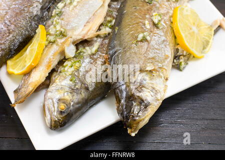 Baked trout fish served on a plate with lemon and spices Stock Photo