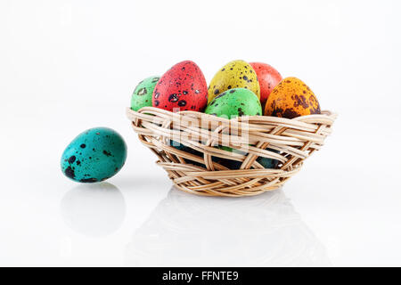 Bright colorful easter eggs. Painted quail eggs in a wicker basket with reflection. Stock Photo